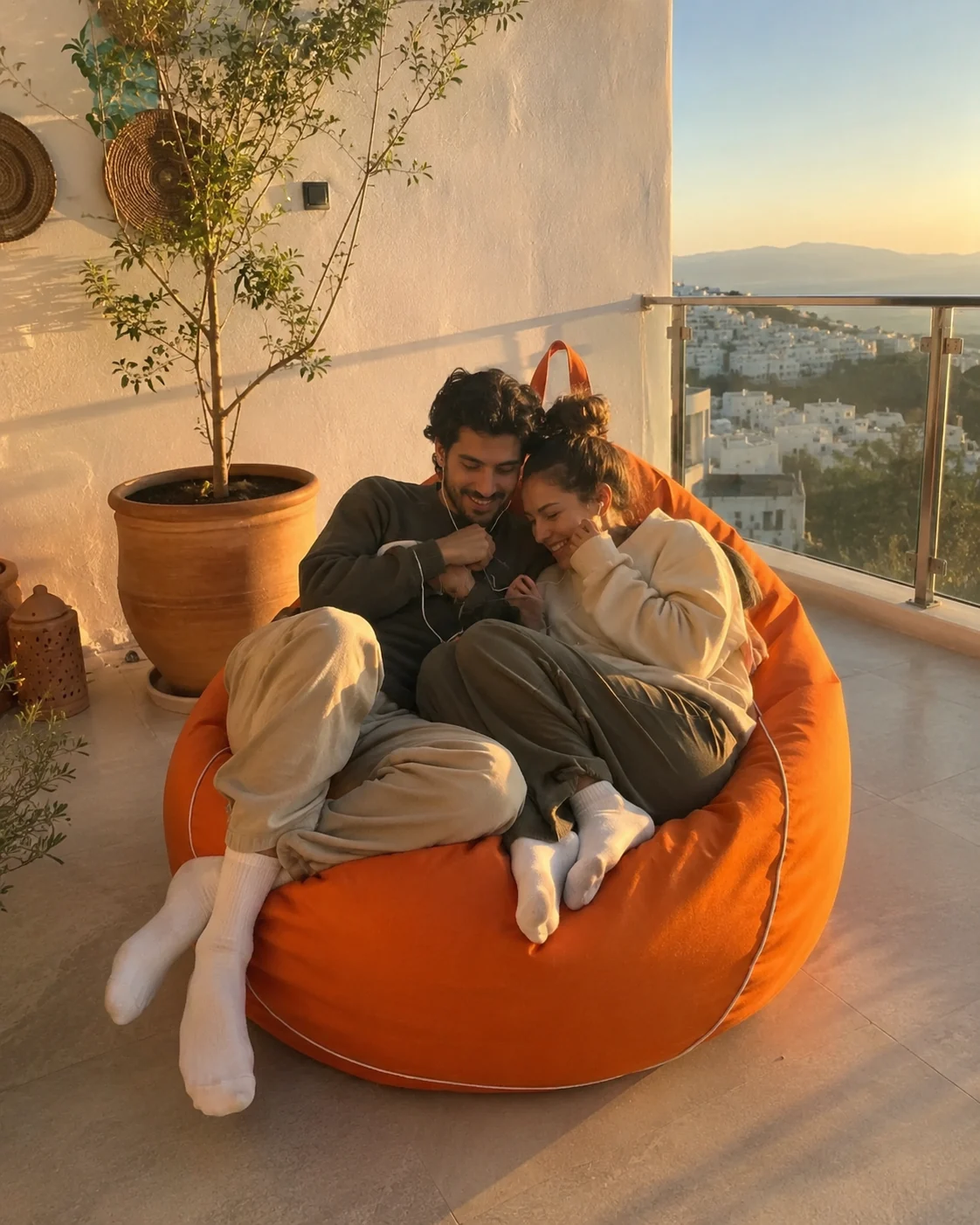 Couple détendu sur un pouf orange face au coucher de soleil