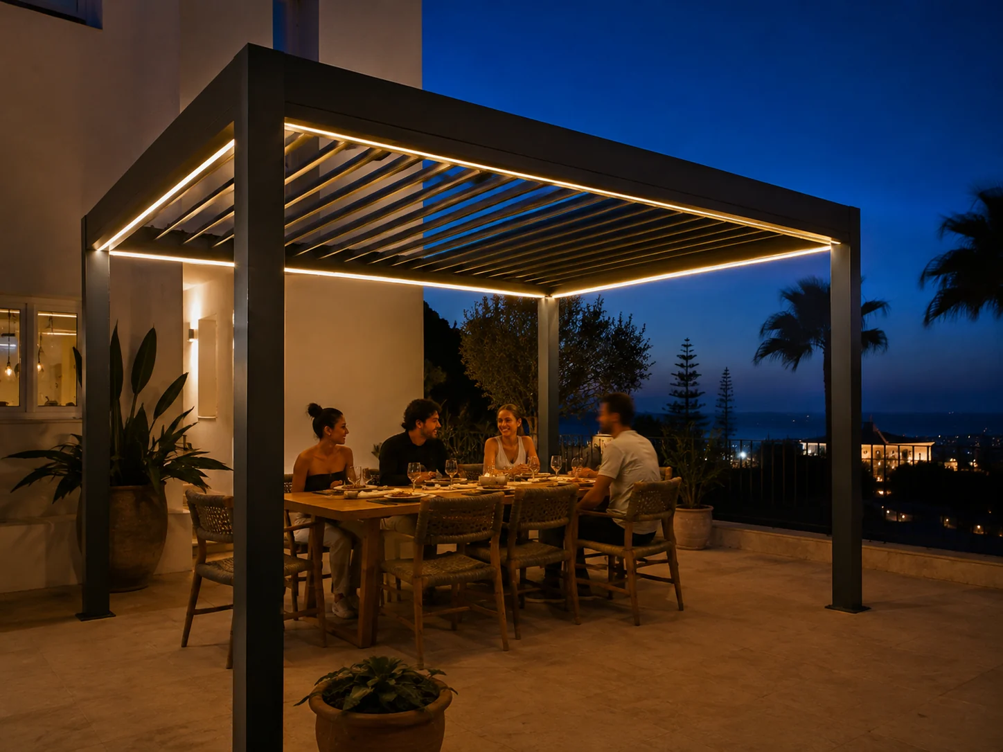 Pergola سوداء مضاءة بإنارة LED مدمجة، وعائلة تتناول العشاء على التراس أمام البحر
